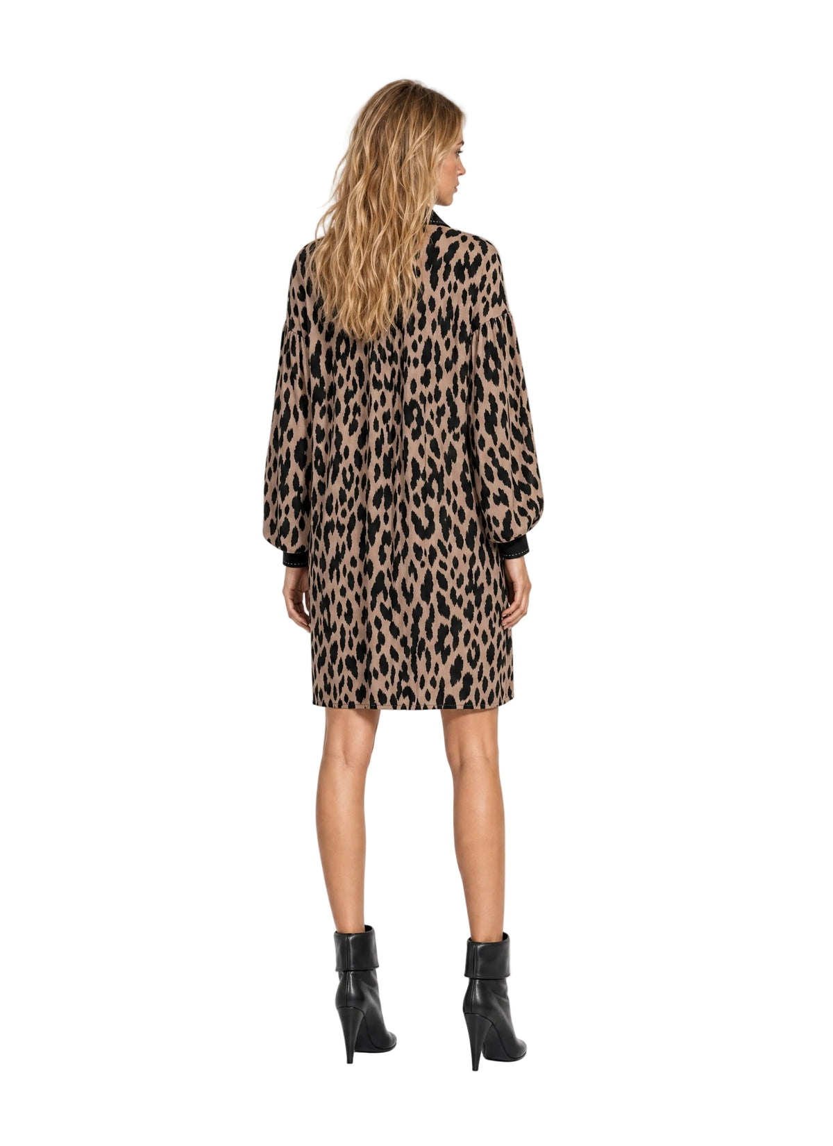 A woman shown from the back wearing a leopard-print long-sleeve shirt dress with black cuffs and black ankle boots, photographed against a plain white studio background.